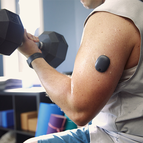 Hombre levantando pesas mientras lleva puesto un sistema de MCG de larga duración para la diabetes.