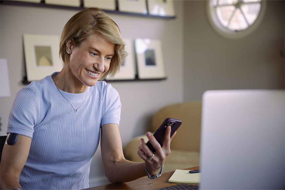 Mujer usando el teléfono para obtener información sobre cómo obtener un sistema de MCG implantable.