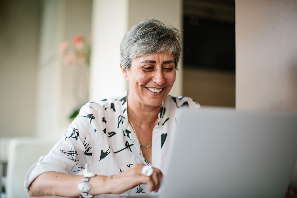 Mujer usando el ordenador portátil para informarse sobre la aplicación de MCG para el monitor inalámbrico de glucosa.