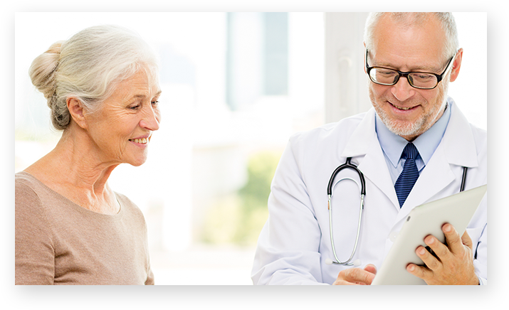 Una paciente y un médico de pie uno al lado del otro mirando una tablet.